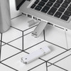 A silver and white USB flash drive is plugged into a laptop, placed on a geometric patterned surface.