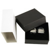 A pair of plain silver cufflinks displayed in a black box, with a white box beside it.