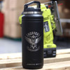 A drink bottle in matte black with a silver logo, featuring a sturdy handle and a rugged design.