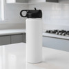 A drink bottle in white with a black lid, featuring a handle, set against a kitchen backdrop.