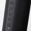A black Bluetooth speaker featuring textured material and control buttons on the side. Contains a branding logo.