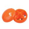An orange pill box with a hinged lid, divided into four compartments, holding various types of pills.