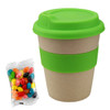 A bamboo cup with a bright green silicone lid and band, accompanied by a bag of colourful jelly beans.