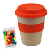 A bamboo cup in natural tones with an orange lid and sleeve, alongside a packet of colourful jelly beans.