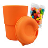 A reusable coffee cup in vibrant orange silicone, accompanied by a bag of colourful jelly beans.