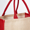 A jute bag featuring a natural and red colour scheme, with sturdy red handles. It includes a logo.