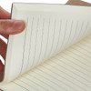 A hand holds a brown Falby notebook with lined, cream-coloured pages. It features a simple design and a logo.