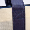 Close-up of a non-woven large zipped shopping bag featuring a navy blue handle and a light beige body.