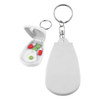 A compact white pill cutter with a keychain attachment and a small container holding green and red pills.