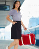 A woman carries a red cotton canvas sports bag with white straps while wearing a grey top and dark skirt.