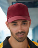 A red polycotton twill cap with a structured front and a curved peak, featuring a logo on the front.