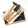 A wooden garden box containing three black-handled gardening tools with wooden grips.