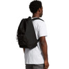 A black recycled rucksack is worn by a person from the side, featuring adjustable straps and a drawstring closure.