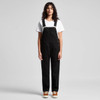A pair of black canvas overalls worn by a model, paired with a white t-shirt and brown shoes.