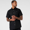 A black short-sleeve button-up shirt featuring a front pocket and a logo on the chest.