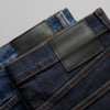 Two pairs of jeans in blue and dark denim, featuring leather patches and contrasting stitching.