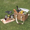 A woven picnic basket filled with drinks, fruits, and snacks, alongside a wooden platter with cheese and meats.