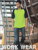 A man in a high-visibility lime green and navy raglan sleeve polo shirt stands on a ladder in a work setting.