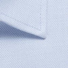 A close-up of a light blue button-up shirt collar made from textured fabric, featuring a logo.