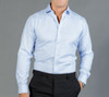 A light blue button-up shirt displayed on a model, featuring a collar and long sleeves. The shirt has a logo.