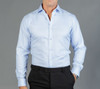 A light blue button-up shirt displayed on a model against a grey background, featuring a logo on the chest.