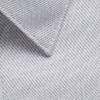 A close-up of a light grey woven fabric with a textured surface, featuring a collar edge and a logo.