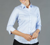 A light blue button-up shirt with three-quarter sleeves, featuring a collar and a row of buttons down the front.