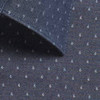 A dark navy chambray fabric featuring small, light-coloured patterns and a collar edge. It includes a logo.