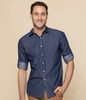 A button-up shirt in navy chambray fabric, featuring rolled-up sleeves and a fitted design. It has a logo on it.