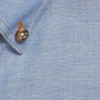 A blue work shirt collar with a button detail, featuring a textured fabric. Branding is present on the shirt.