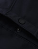 A close-up of a navy softshell jacket featuring a snap button and interior stitching details.