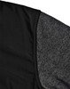 A black quilted jacket featuring a heather grey sleeve. Includes a logo on the fabric.