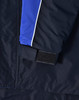A close-up of a navy jacket featuring blue and white detailing, with a Velcro cuff closure. It has a logo on it.