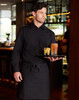 A man in a black cotton/poly stretch long-sleeve shirt holds a tray with drinks, wearing a matching black apron.
