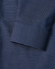 A close-up of a navy men's button-up shirt featuring a pin dot pattern and a cuff detail.