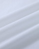 A close-up of white cotton fabric with soft, smooth texture, featuring natural wrinkles and folds.