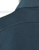 A close-up of a dark green polo shirt, featuring a textured fabric and a collar. The shirt has a logo present.