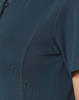 A close-up of a teal polo shirt featuring a collar and a textured fabric. The shirt has a small logo.