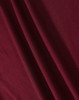 A close-up of a textured fabric in a rich burgundy colour, showcasing its drape and weave.