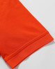 An orange polo shirt featuring a textured fabric and a folded sleeve hem. It includes a logo on the garment.