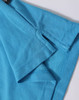 A close-up of a turquoise polo shirt, featuring a branded label and detailed fabric texture.