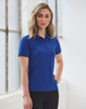 A woman stands wearing a ladies' textured polo shirt in blue, featuring a collar and a logo.