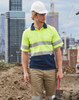 A hi-vis yellow and navy safety polo shirt featuring reflective 3M tape, worn by a male construction worker.