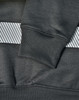 A close-up of a dark green jumper featuring a grey striped pattern and ribbed cuffs, with a branding logo.