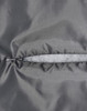 A close-up of a grey quilted fabric with a zip closure, highlighting the texture and stitching details.