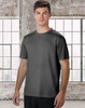 A men's short sleeve tee in grey, featuring a minimal design and a logo. The model stands against a large window background.