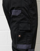 A close-up of black cargo pants featuring grey accents and a logo on the side.