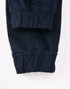 A pair of navy unisex cotton stretch drill cuffed work pants with gathered cuffs. Features a logo on the waistband.