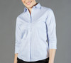 A light blue, striped women's shirt with a collar and three-quarter sleeves. It features a logo on the chest area.