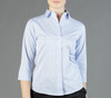 A light blue, long-sleeved shirt with a collar and buttons, featuring a fitted design. It has a branding logo.
